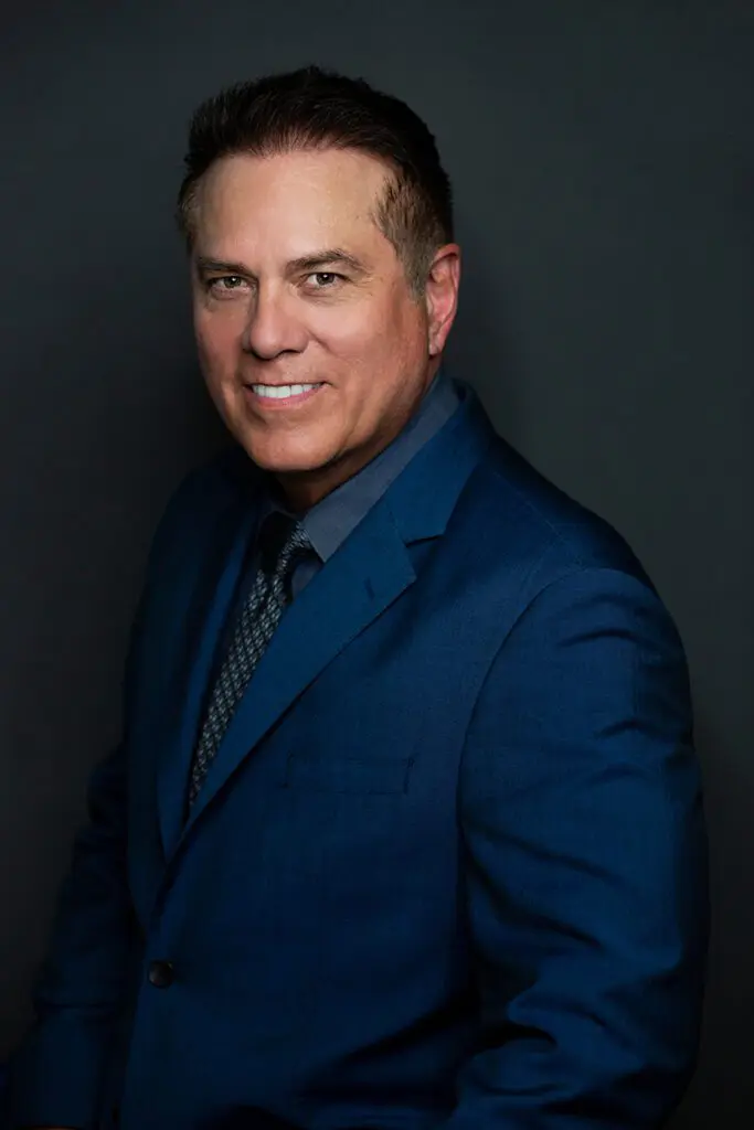 A man in a suit and tie smiling for the camera.